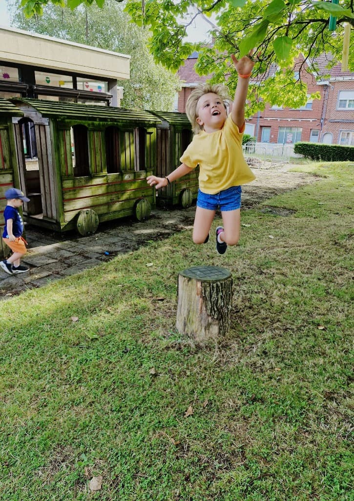 Meisje springt vrolijk van een boomstronk